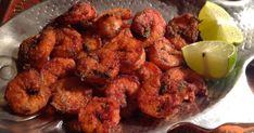 fried shrimp on a silver plate with lemon wedges