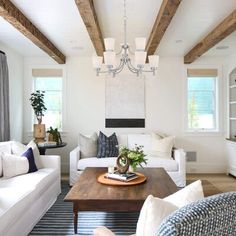 a living room filled with white furniture and wooden beams