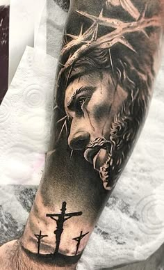 a man's arm with jesus on the cross and crown of thorns tattoo design