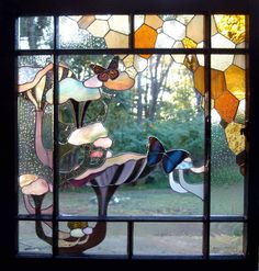 a close up of a stained glass window with flowers and birds in the background,