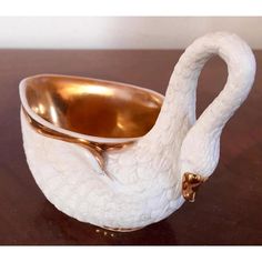 a white swan shaped bowl sitting on top of a wooden table