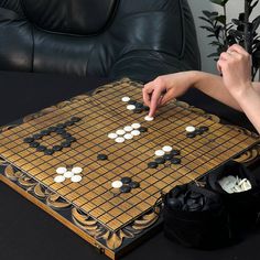 a person playing a board game with white and black pieces on it, sitting in front of a leather chair