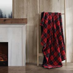 a red and black blanket sitting next to a fireplace