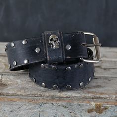 Aged Leather Belt with a Skull loop design, studs and Grommets accents.  . Our Aging / Relic process is carefully made by Hand, from the leather to the Hardware, giving this unique Strap Authenticity and the Style we love like it  already lived for decades.  Features: Designed with Chicago screws that allows you to easily remove and replace the Buckle.  .Leather: 7-8oz (4-5 mm thick) premium vegetable tan leather, great thickness for durability and comfort that will age beautifully with time.      .Width : 2 inches wide. .Color: BLACK. hand dyed with a rich Finish  .Hardware and studs: Antique Nickel. .Size:     -PLEASE CHOOSE YOUR SIZE VERY CAREFULLY -- .Our recommendation and most accurate way to Choose your size as shown in the Picture.  Our mission is for you to pick the correct size a Black Leather Belt With Edgy Style, Black Punk Belt With Rivets, Black Leather Belt With Rivets, Black Leather Belts With Rivets, Adjustable Leather Belt Buckles With Rivets, Adjustable Black Belts With Rivets, Adjustable Black Belts With Studs, Adjustable Black Belt With Studs, Adjustable Black Belt Buckles With Rivets