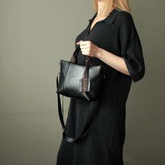 "Black crossbody tote bag small size city style handmade. Mini shoulder bag black color faux leather. Height:18 cm  ( 7,09 \" ) Top Width:29 cm  ( 11,41 \" ) Bottom Width: 21 cm ( 8,26 \" ) Depth:8 cm   ( 3,15 \" ) Strap:115 cm  ( 45,27 \" ) adjustable Black mini tote cross bag made of faux leather. Small black handbag has cotton lining, 3 pockets inside, detachable adjustable strap nylon black. The bag is decorated with a ribbon with a floral pattern. The front of the bag is decorated with two seams, the back of the bag is decorated with a ribbon with a pattern. The bag can be worn both on one side and on one side.  The handbag is decorated with a keychain. Fashion mini black handbag for women. Black small shoulder bag vegan leather handmade. Unique small cross tote bag black vegan leathe Trendy Black Handheld Shoulder Bag, Rectangular Black Shoulder Bag For Fall, Black Rectangular Shoulder Bag For Fall, Trendy Handheld Black Bucket Bag, Black Satchel Box Bag For On-the-go, Black Leather Bucket Bag With Adjustable Handle, Black Top-handle Shoulder Bag For Fall, Black Shoulder Bag For Fall, Casual Black Handheld Shoulder Bag