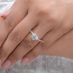 a close up of a person's hand with a diamond ring on their finger