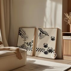 two framed pictures sitting on top of a wooden floor next to a chair and window