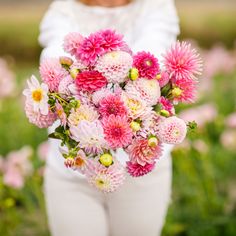 a woman holding a bouquet of pink and white flowers