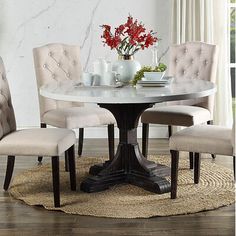 a round dining table with four chairs around it and a vase on the table top