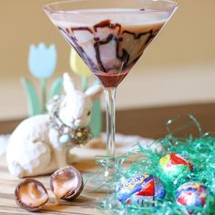 a glass filled with liquid sitting on top of a table next to an easter bunny