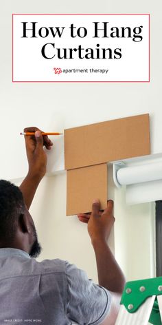 a man is painting the wall with white paint and brown cardboard boxes on top of it