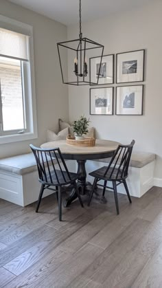 a dining room table with four chairs and a bench in front of the window that has pictures on the wall above it