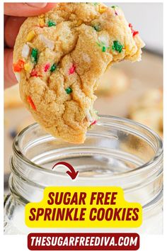 a hand holding a sugar free sprinkle cookie over a jar full of cookies