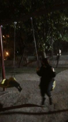 a young child swinging on a swing set at night