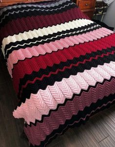 a crocheted blanket on a bed in a room with wooden floors and drawers