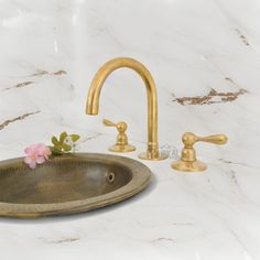 a bathroom sink with two faucets and a flower on the counter next to it