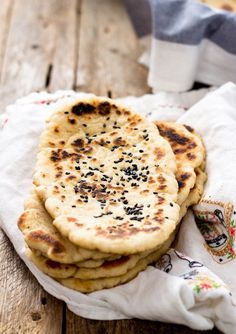 several flat breads are stacked on top of each other with black sesame sprinkles