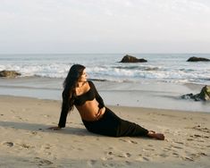 a woman laying on top of a sandy beach next to the ocean