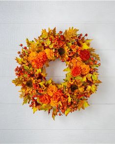 a wreath with orange and yellow flowers hanging on a wall