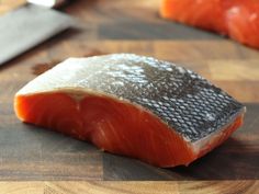 a piece of raw salmon sitting on top of a wooden cutting board