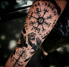 a person with a tattoo on their arm holding a compass and other things in the background