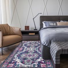 a bedroom with a bed, chair and rug in front of a window that has geometric wallpaper on it