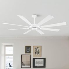 a white ceiling fan mounted to the side of a wall in a room with pictures on it