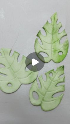 three green leaf cutouts on a white wall