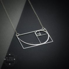 "Meet your perfect necklace (literally!) This necklace embodies the rectangle and its logarithmic spiral, makes for the ultimate teacher gift, gift for science lovers and math aficionados alike, ★This is the silver item, for the gold item use this link: https://www.etsy.com/listing/608481649 ♥WANT TO MAKE IT PERSONAL? ♥ Add a charm letter to your necklace - Add this item: https://www.etsy.com/il-en/listing/687931684 ★ Comes in our signature gift box, ready for gift giving. ★ Available in Silver Golden Ratio Necklace, Fibonacci Necklace, Logarithmic Spiral, Fractal Geometry, Jewelry Design Studio, Science Jewelry, Geek Jewelry, Chevron Necklace, Golden Triangle