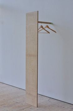 an empty room with a coat rack and clothes hangers on the wall next to it