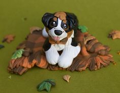 a small dog figurine sitting on top of a green surface next to leaves