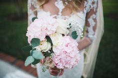 a bride holding a bouquet of pink and white flowers