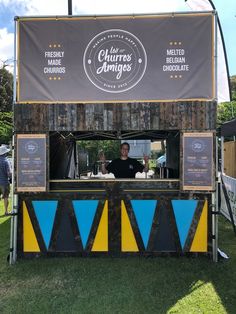 a man standing behind a food cart at an outdoor event