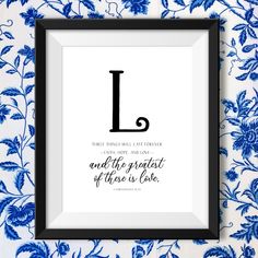 a blue and white floral print with the letter l in black frame on a wall