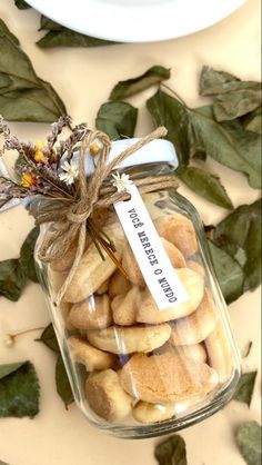 a jar filled with cookies sitting on top of a table next to leaves and a plate