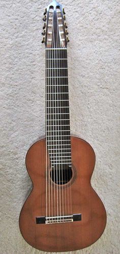 an acoustic guitar hanging on the wall next to it's stringy strings and frets