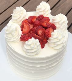 a white cake topped with whipped cream and strawberries