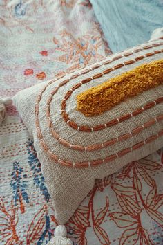 a close up of a pillow on a bed with an orange and white border around it