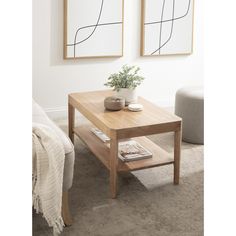 a living room with two paintings on the wall and a coffee table in front of it