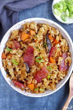 a bowl filled with rice and vegetables next to a wooden spoon on a blue cloth