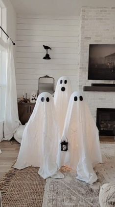 two white ghost statues sitting in front of a fireplace with black eyes on their heads