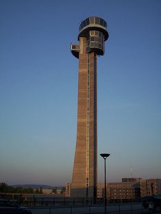 a tall tower with a clock on it's side next to a parking lot