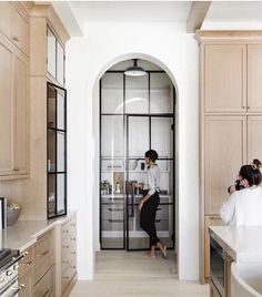 two women are standing in the kitchen looking at something on the counter and behind them is an open door