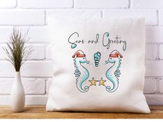 a white pillow with two seahorses on it and the words seas and greeting