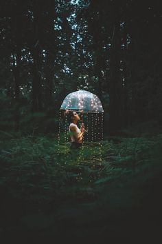 a person holding an umbrella in the middle of a forest with words written on it