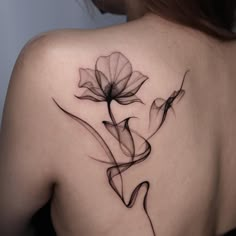 the back of a woman's shoulder with a flower tattoo on her left shoulder