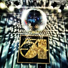 a disco ball hanging from the ceiling in front of a sign that says gq