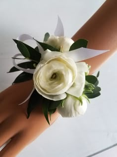 a close up of a person's hand holding a white flower and ribbon bouquet