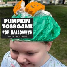 a young boy wearing a paper bag on his head with the words pumpkin toss game for halloween