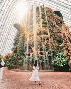 a woman standing in front of a waterfall at the gardens by the bay, singapore